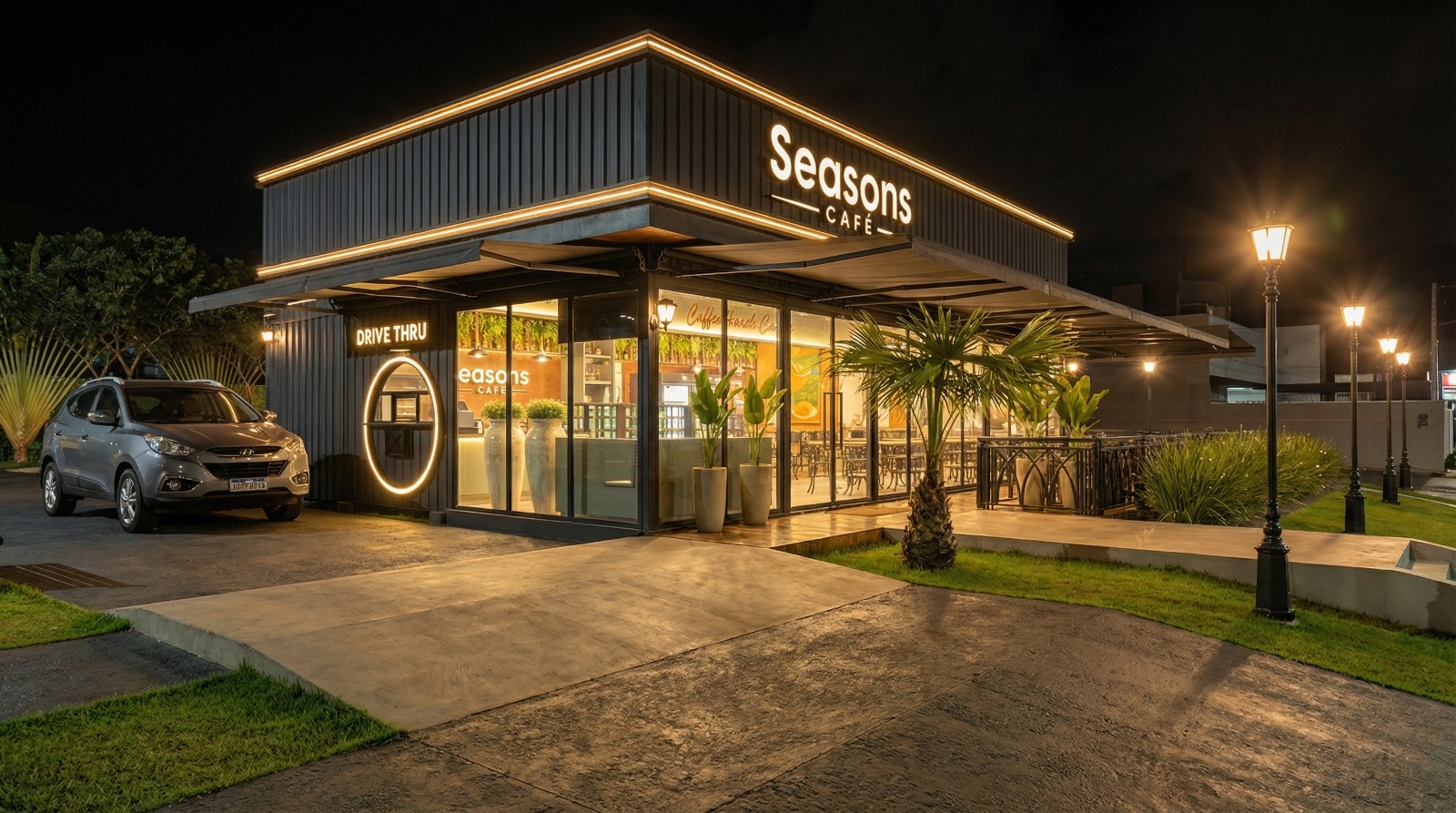 Fachada do Seasons Café à noite com letreiro iluminado e a entrada do Drive Thru