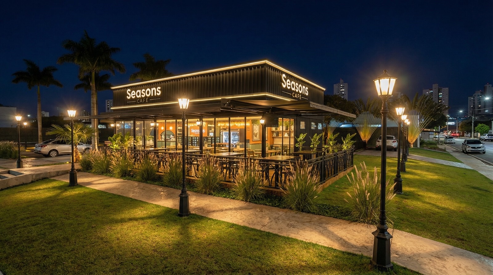 Fachada do Seasons Café à noite, com letreiros iluminados, palmeiras e área externa aconchegante